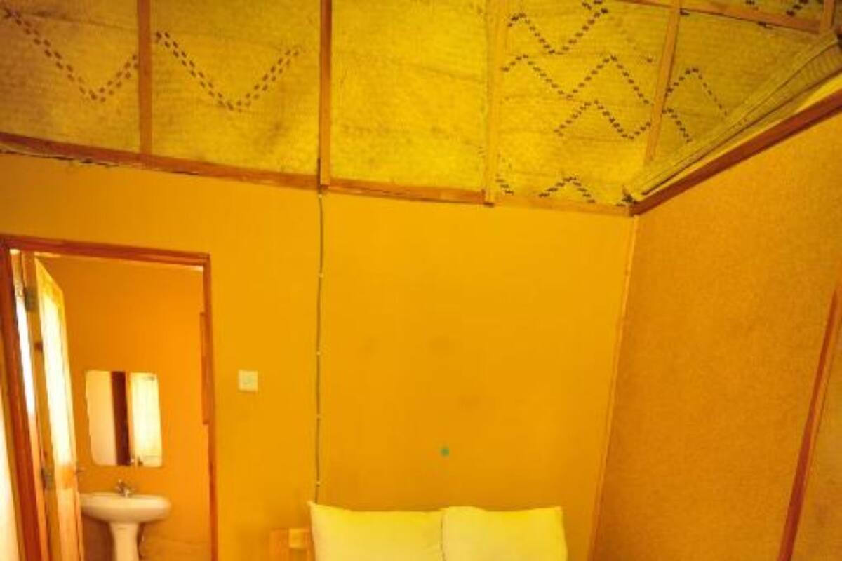 A single bed with a zebra print bedspread, a wooden floor, a small bedside table, and a plain wall.
