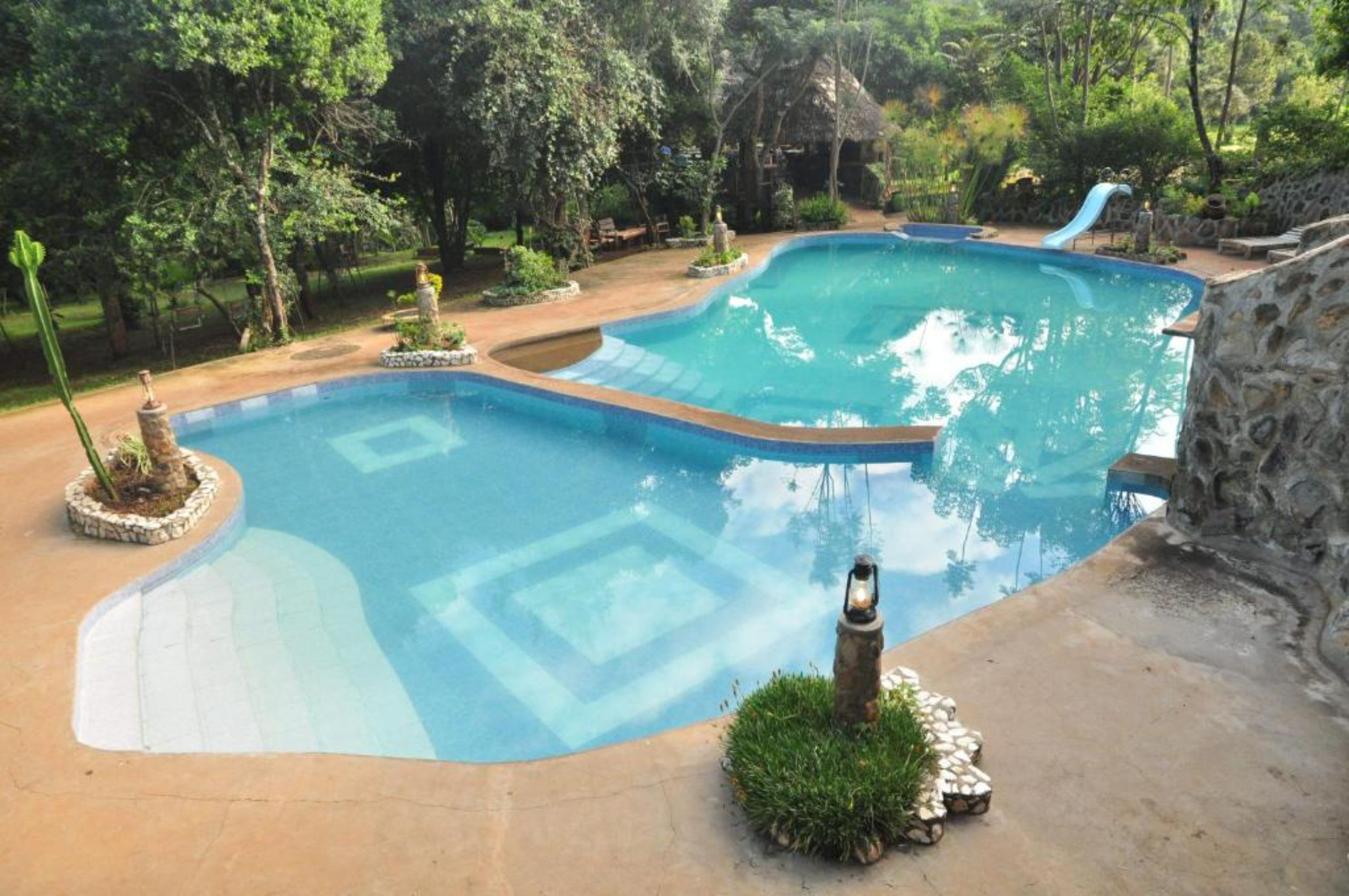 A swimming pool with a stone wall and a small waterfall feature.