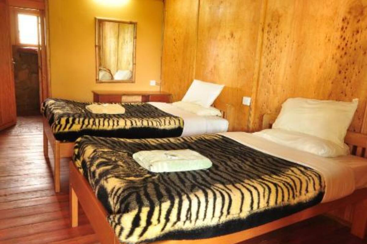A cabin-style room with two wooden beds, a wooden floor, and a wooden ceiling.