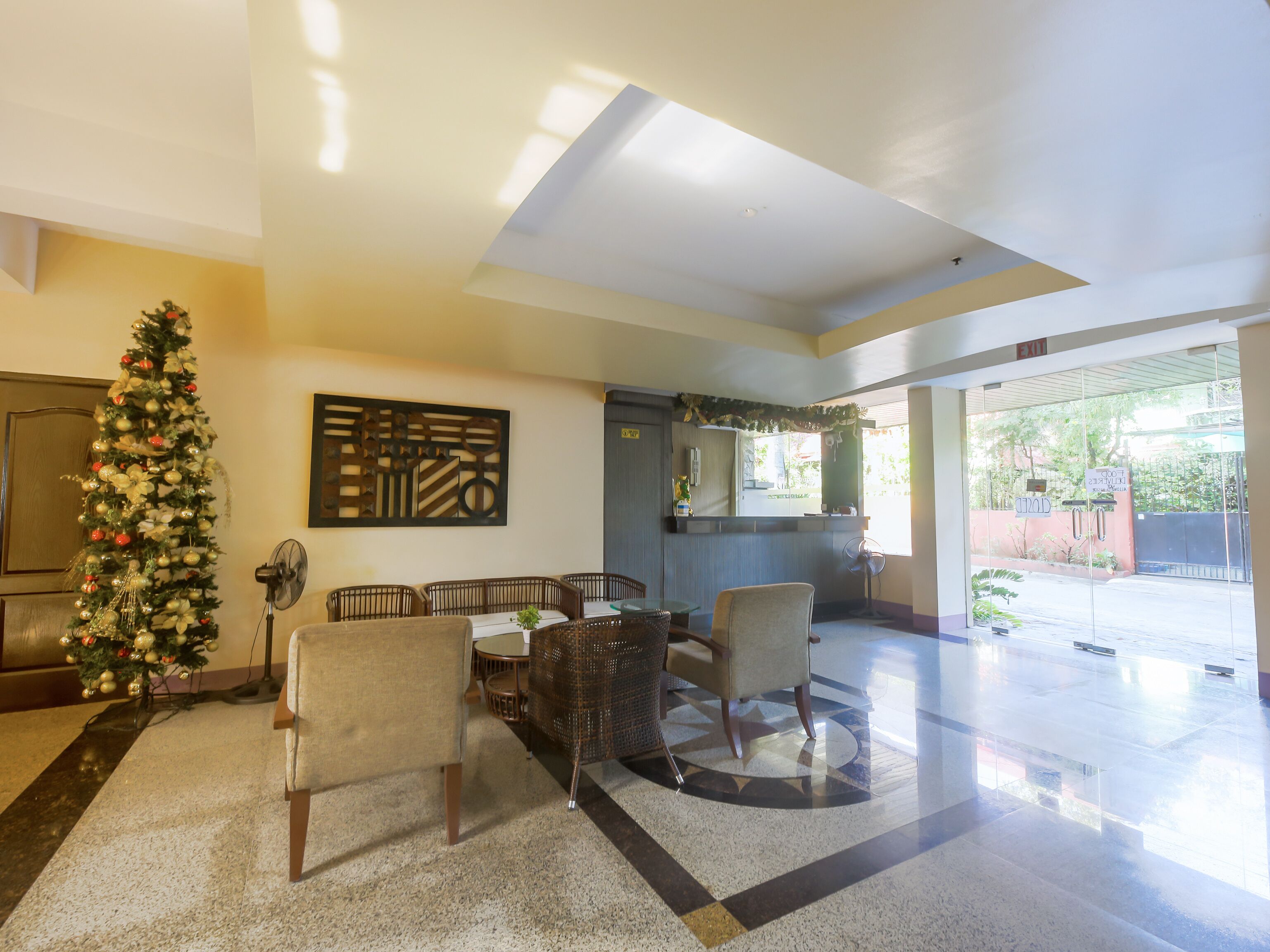 A lobby with a Christmas tree, seating area, and a large window.
