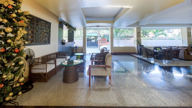 Um hall amplo com árvore de Natal, móveis de vime e uma mesa de centro de vidro.