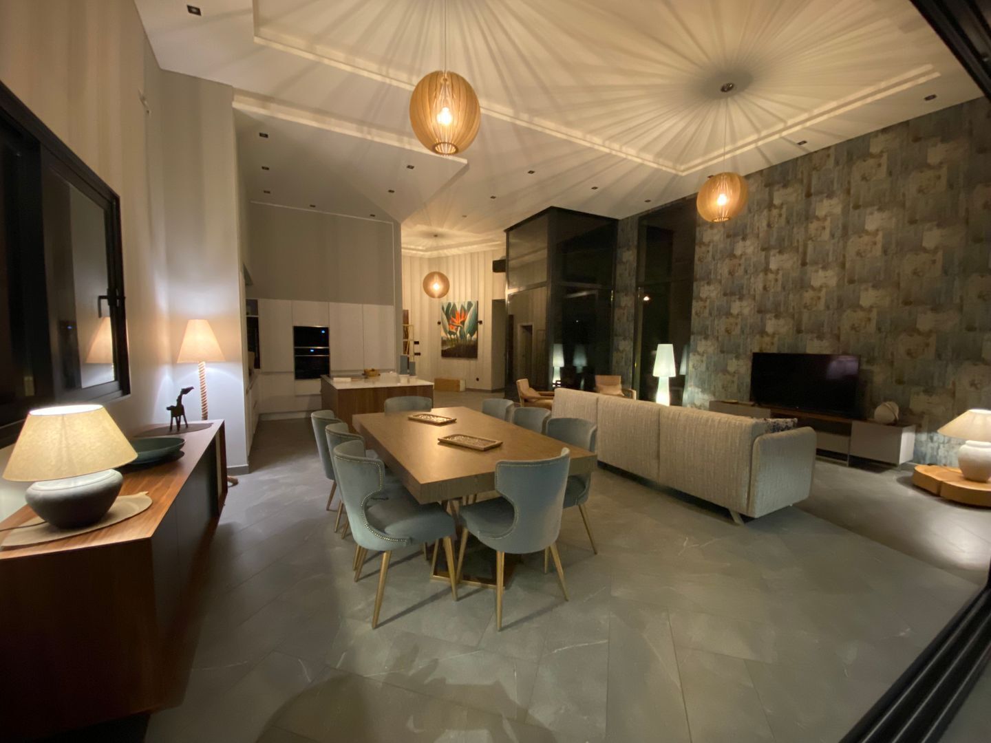 Una sala de estar moderna con comedor, que incluye un sofá grande, un televisor y una chimenea.