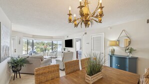 A dining area with a wooden table, wicker chairs, and a chandelier. - Great Marina Views, Steps to Pool, Bike to Beach (Hilton Head Island)