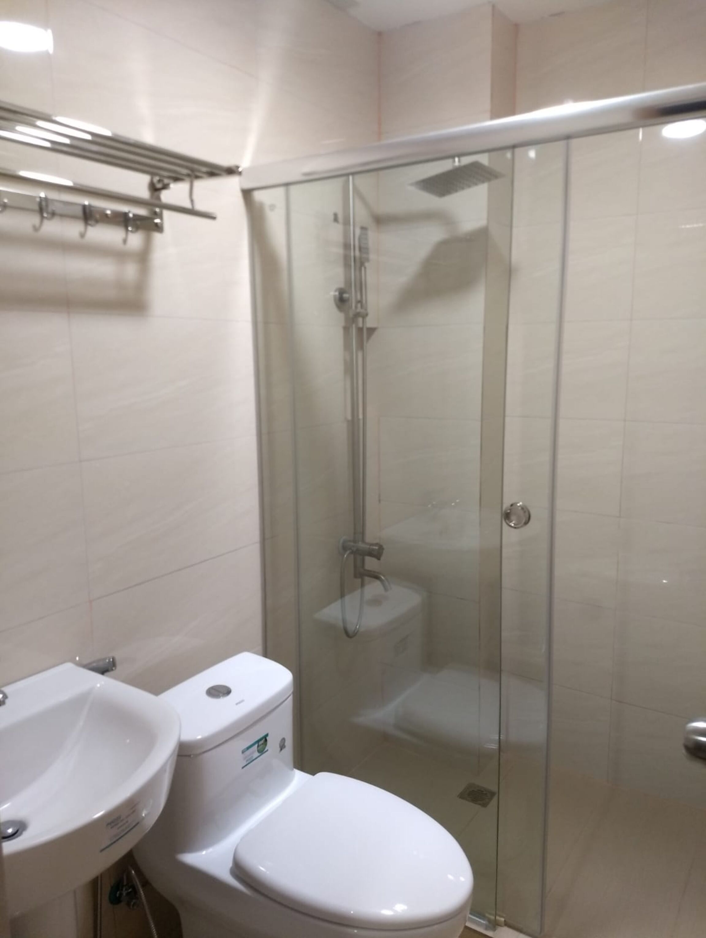 A modern bathroom with a glass-enclosed shower, a white toilet, and a sink.