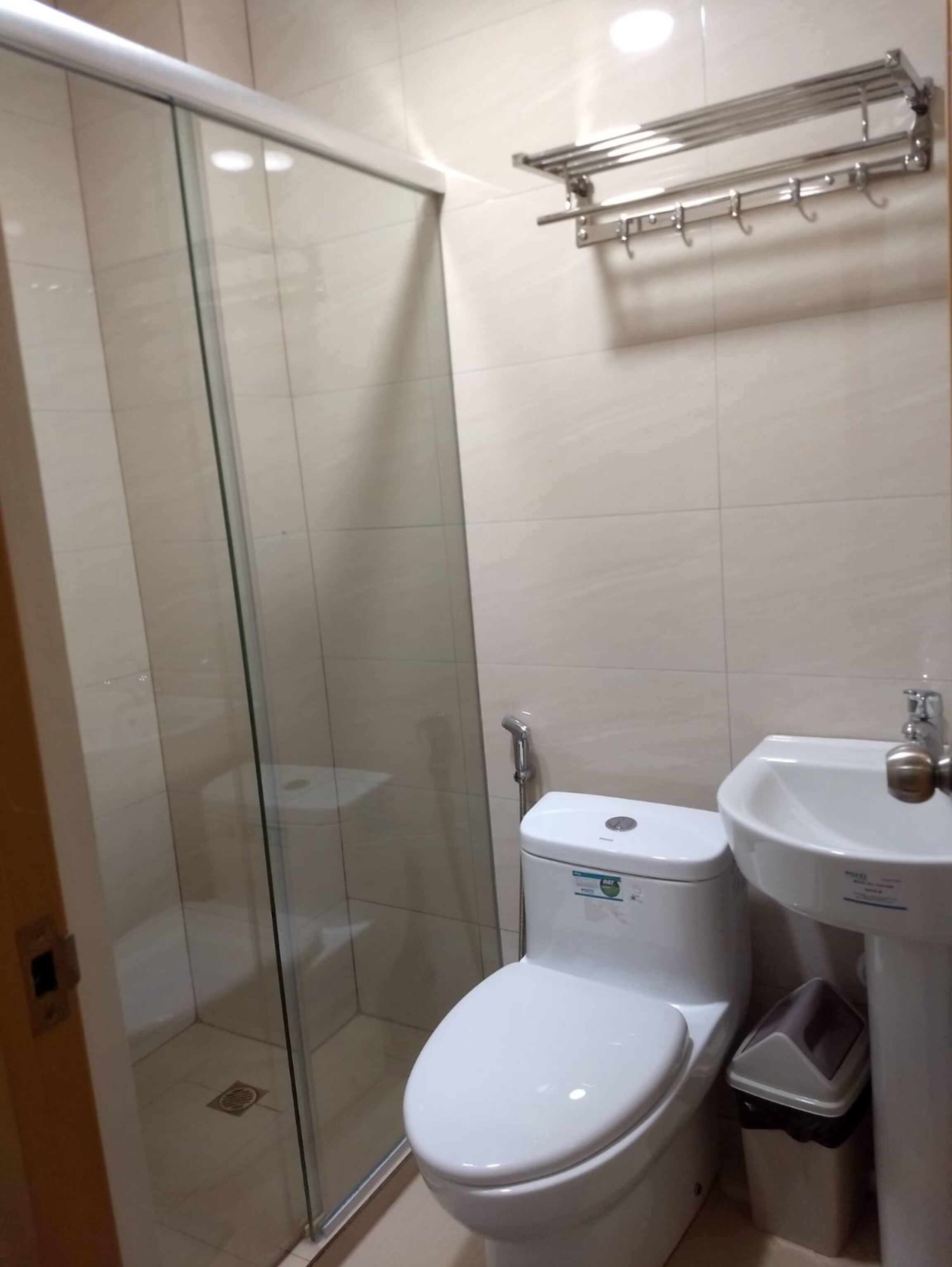 A bathroom with a glass-enclosed shower, a toilet, and a sink.