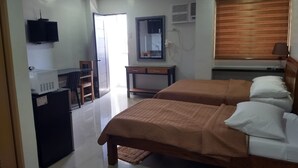 A hotel room with two beds, a desk with a computer, a television, and a mirror.
