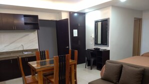 A compact living space with a kitchenette, a dining area, a workspace, and a sofa.