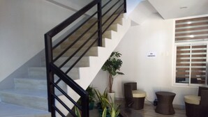 A staircase with a black railing, potted plants, and a 'NO SMOKING' sign on the wall.