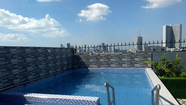 A rooftop swimming pool with a cityscape view, tiled flooring, and metal railings.
