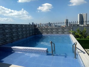 A rooftop swimming pool with a cityscape view, tiled flooring, and metal railings. - OYO 848 Dona Aurora Condotel (Quezon City)