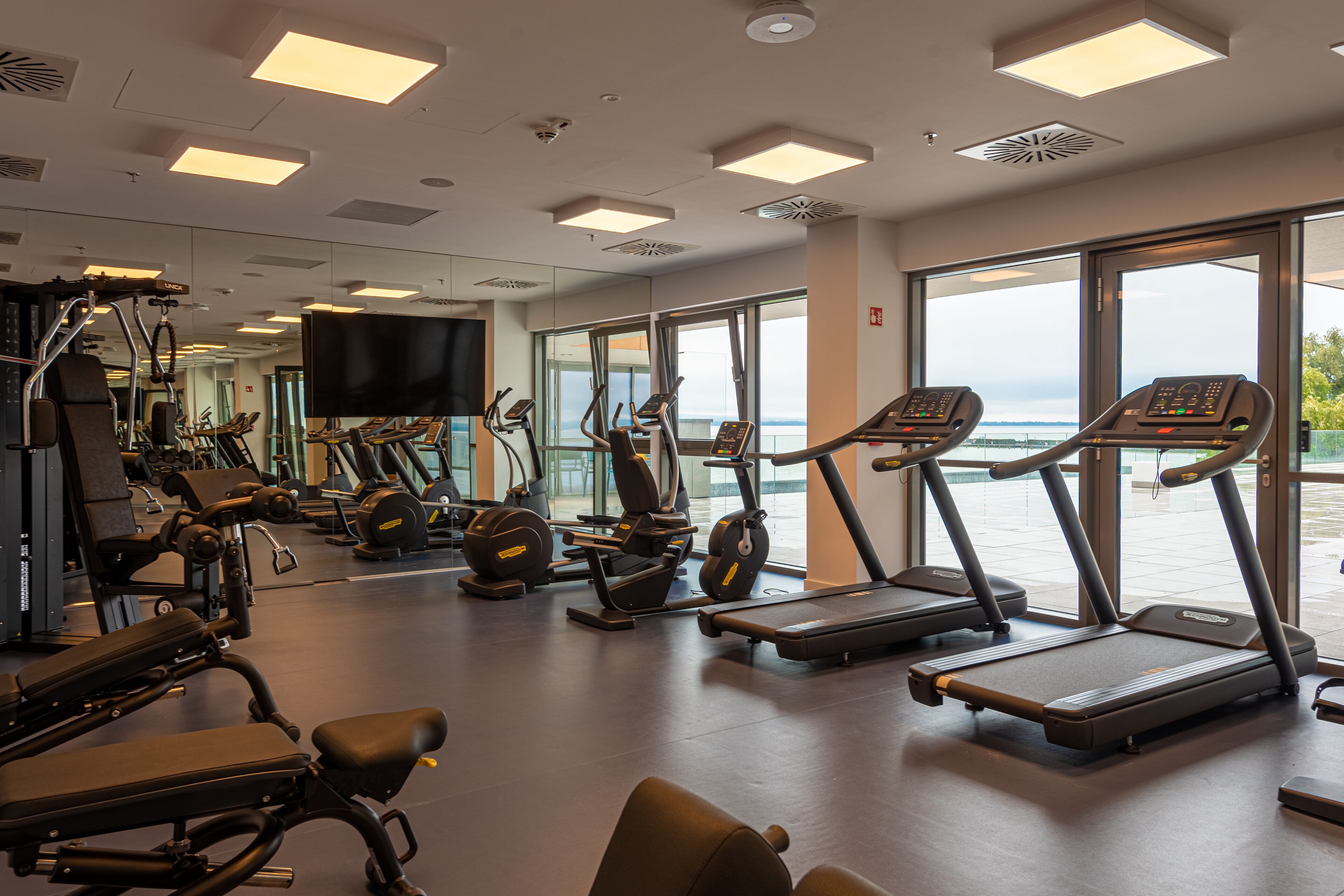 Un gimnasio con cintas de correr, elípticas y equipo de pesas.