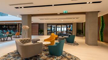 A modern lobby with seating areas, a bar, and a green wall.