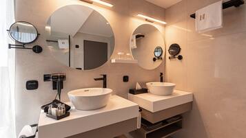 Een moderne badkamer met twee wasbakken, ronde spiegels en een haardroger.
