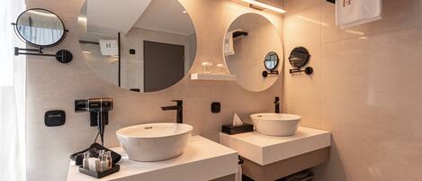 Un baño moderno con dos lavamanos, espejos redondos y un secador de pelo.