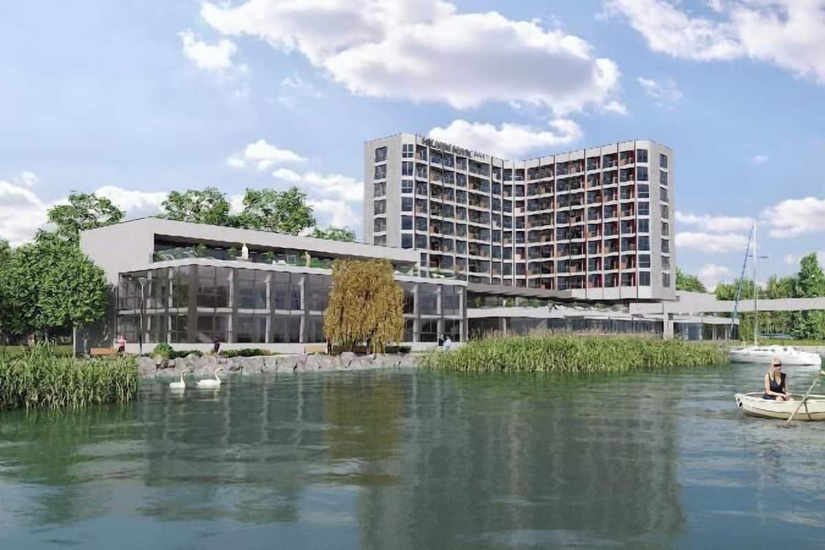 Ein modernes Hotel mit geschwungener Fassade, einem Glaseingang und Blick auf das Wasser.