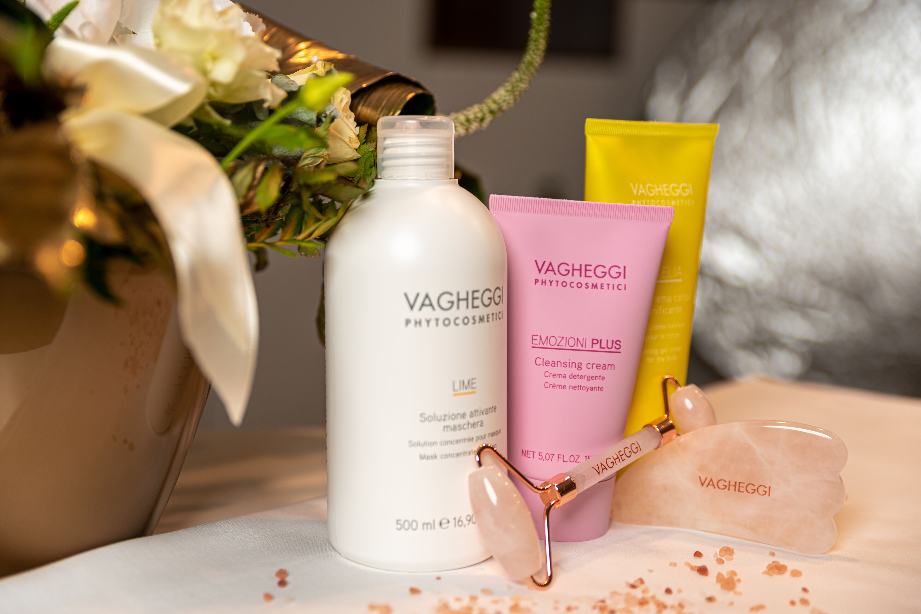 A bottle of Vagheggii Phytocosmetic cleansing cream, a pink tube of Vagheggii Phytocosmetic Emozioni Plus cleansing cream, and a jade roller with the Vagheggii logo.