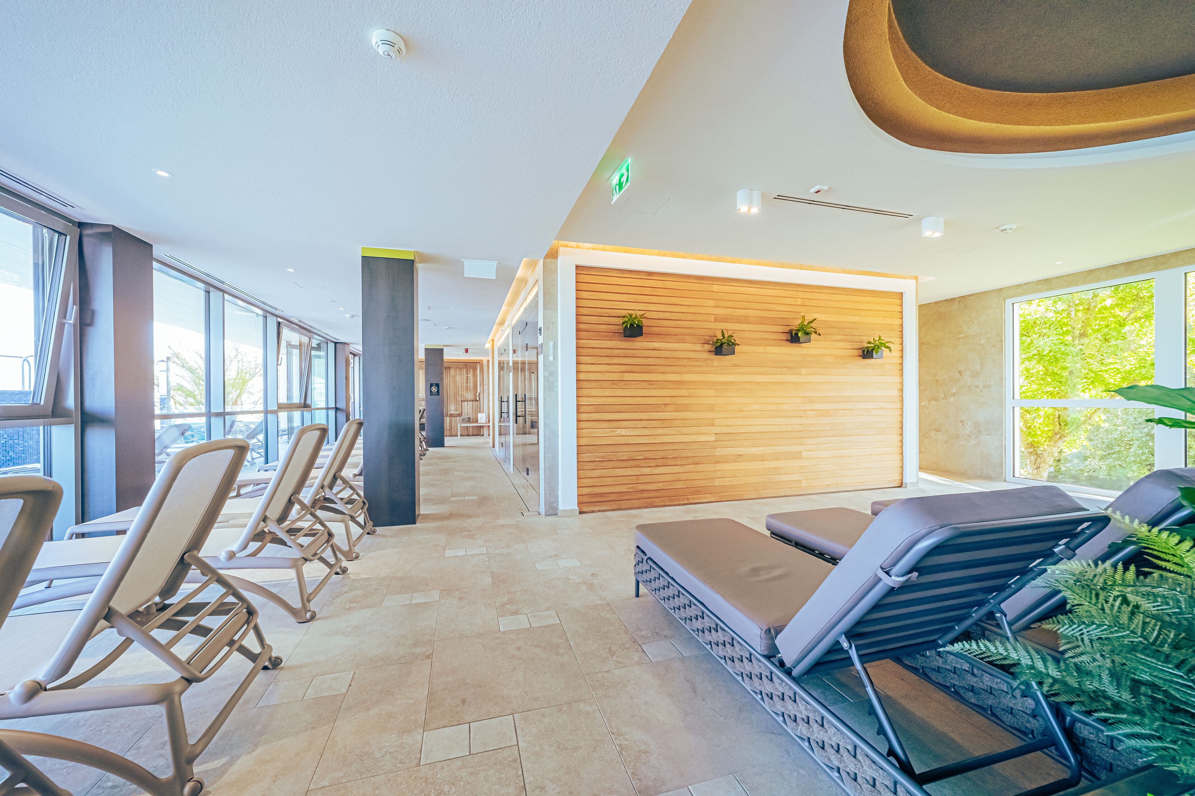 Un área de spa moderna con tumbonas y una pared de madera con plantas.