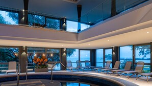 Zona moderna de piscina interior con sillones de descanso y vistas al agua.