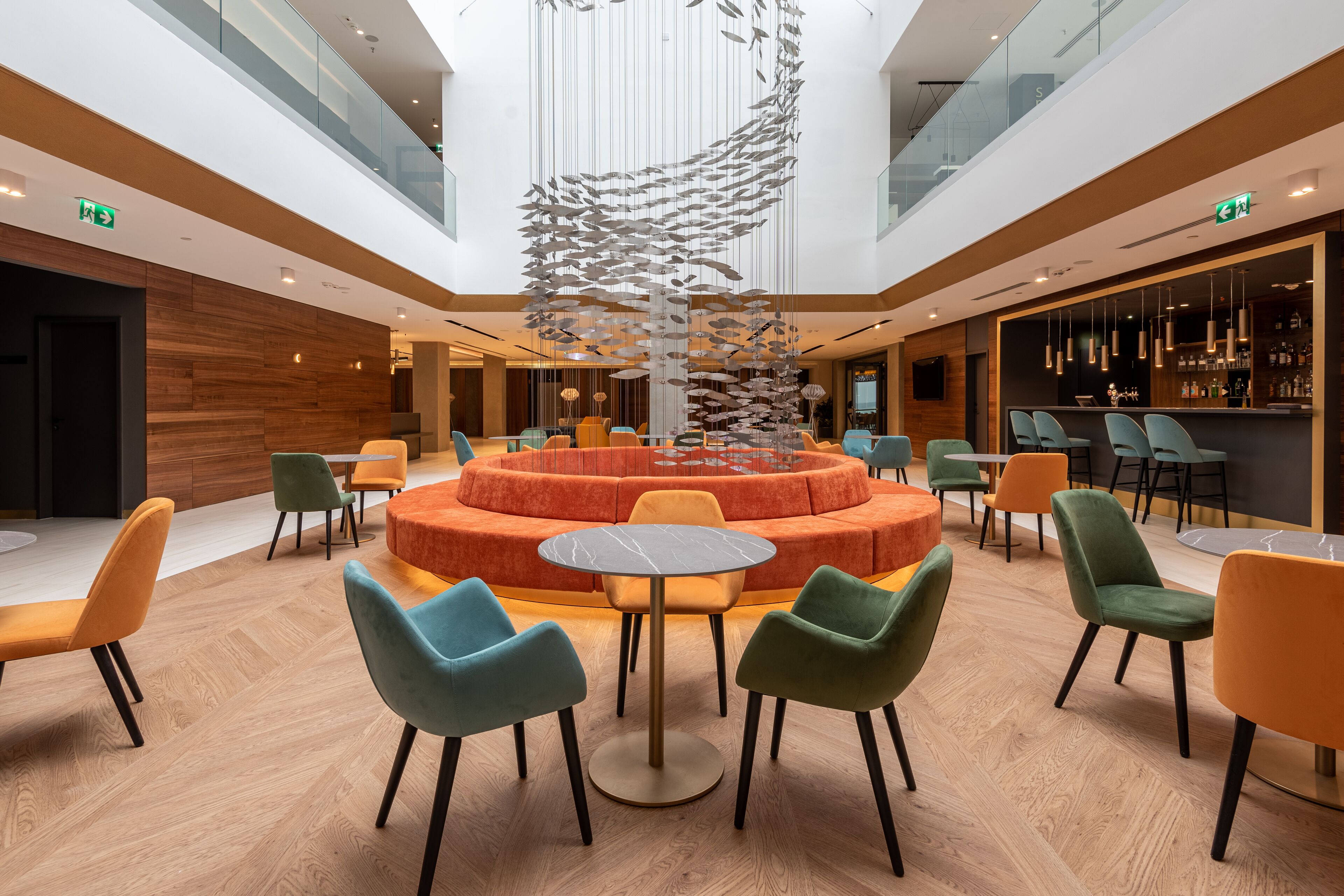 A modern hotel lobby with a central seating area, a bar, and a decorative fish sculpture.