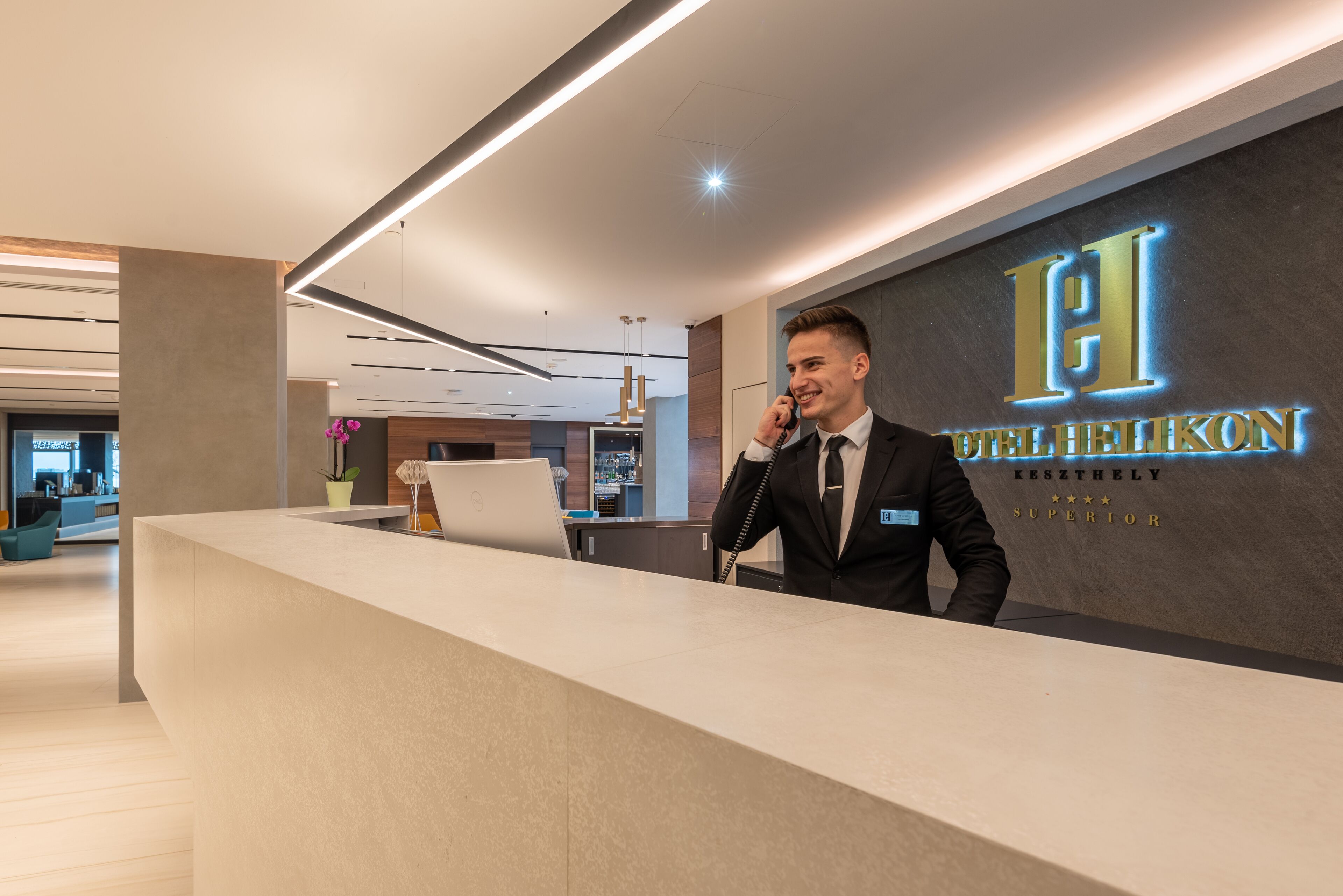 A hotel reception desk with a modern design, a laptop, and a sign indicating the hotel name and rating.
