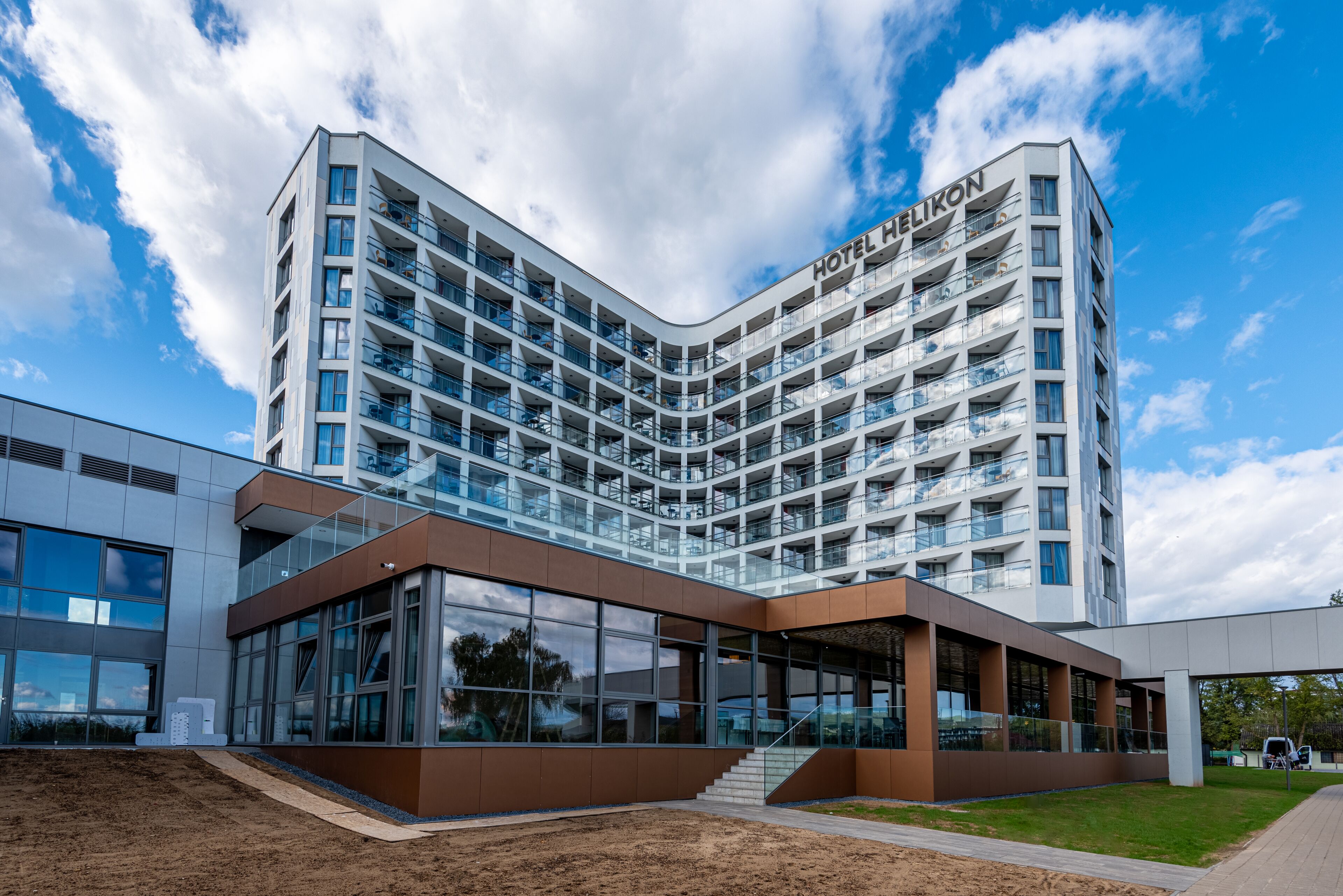 A modern hotel with a curved facade, multiple balconies, and a glass entrance.