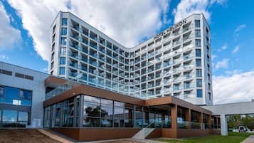 A modern hotel with a curved facade, multiple balconies, and a glass entrance.