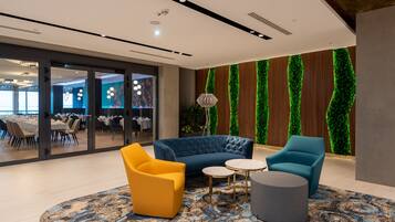A modern lounge area with a blue sofa, yellow armchair, and grey ottoman.
