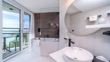 Un baño moderno con una bañera grande, un espejo redondo y un lavabo blanco.