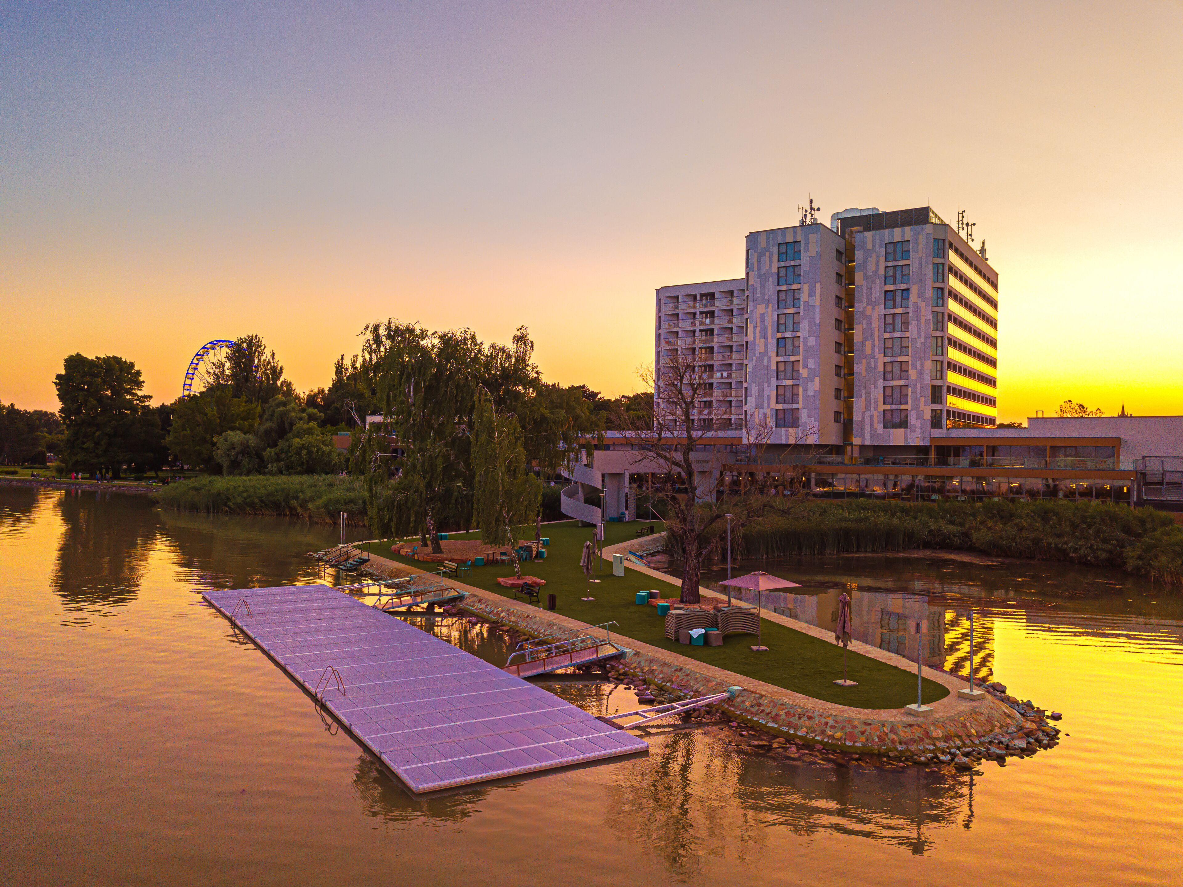 A waterfront hotel with a dock, a swimming pool, and a large building with multiple floors.