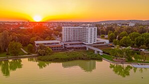 Un hotel moderno con un patio central, rodeado de vegetación y una masa de agua.