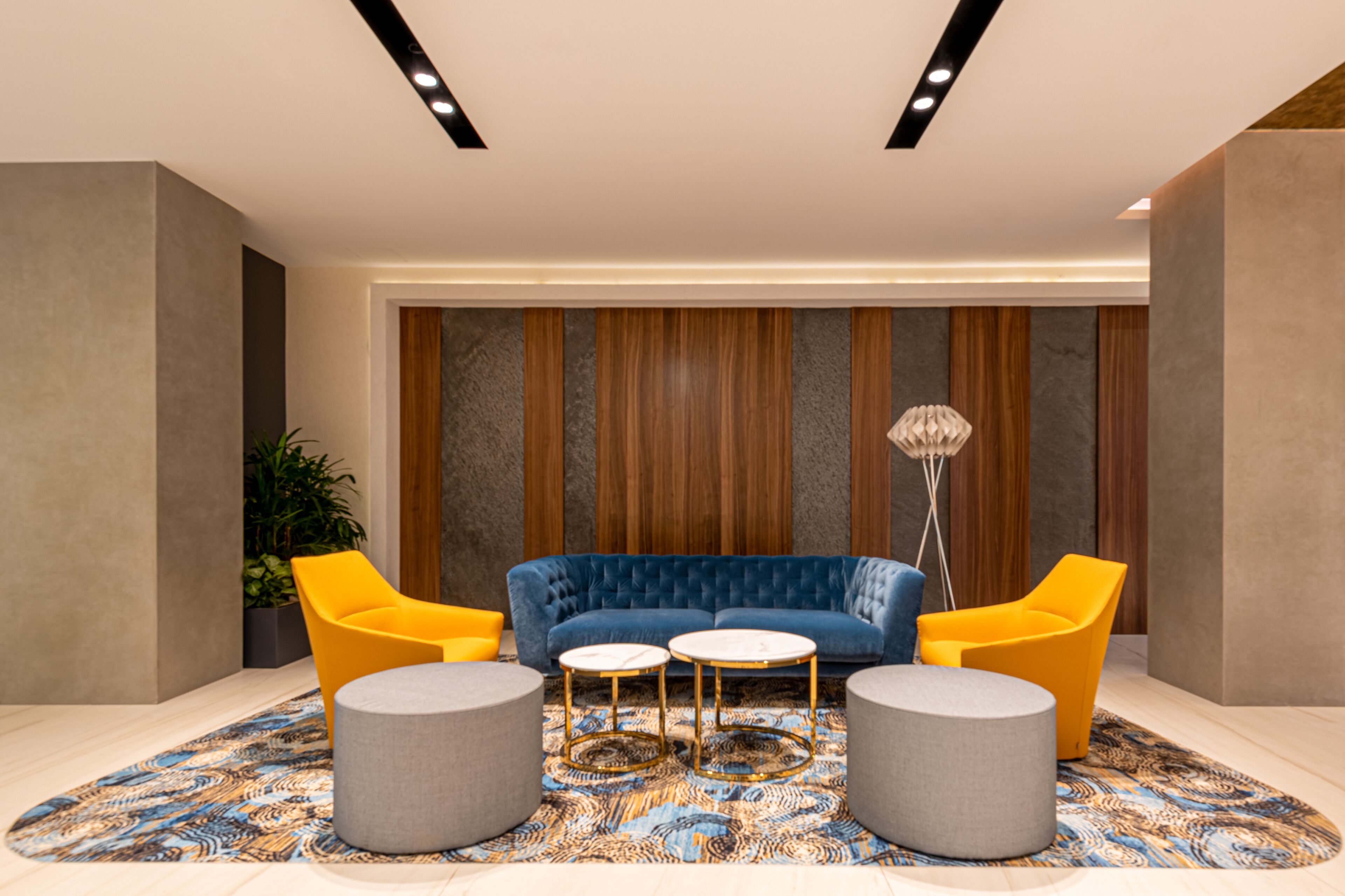 Eine moderne Lobby mit einem blauen Sofa, gelben Sesseln und einem gemusterten Teppich.