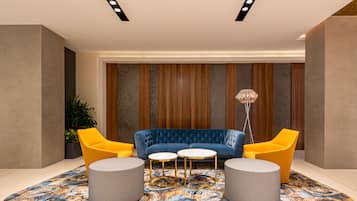 Um hall moderno com um sofá azul, cadeiras amarelas e um tapete estampado.