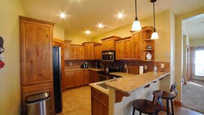 A kitchen with wooden cabinets, a stainless steel refrigerator, a microwave, and a granite countertop. - Perfect Mountain Family Condo Near Grand Targhee and Driggs (Driggs)