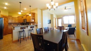 A spacious kitchen with wooden cabinets, a dining area with a large table and chairs, and a ceiling fan. - Perfect Mountain Family Condo Near Grand Targhee and Driggs (Driggs)