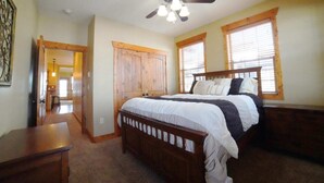 A bedroom with a wooden bed, a ceiling fan, and two windows with blinds. - Perfect Mountain Family Condo Near Grand Targhee and Driggs (Driggs)