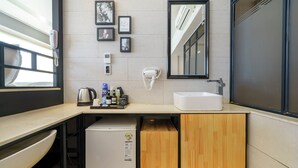 A modern bathroom with a sink, mirror, and framed pictures on the wall. - JK Hotel (Busan)