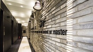 A hallway with a brick wall and a sign that reads "Master control or master." - JK Hotel (Busan)