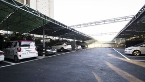 A parking area with multiple cars and a covered walkway. - JK Hotel (Busan)