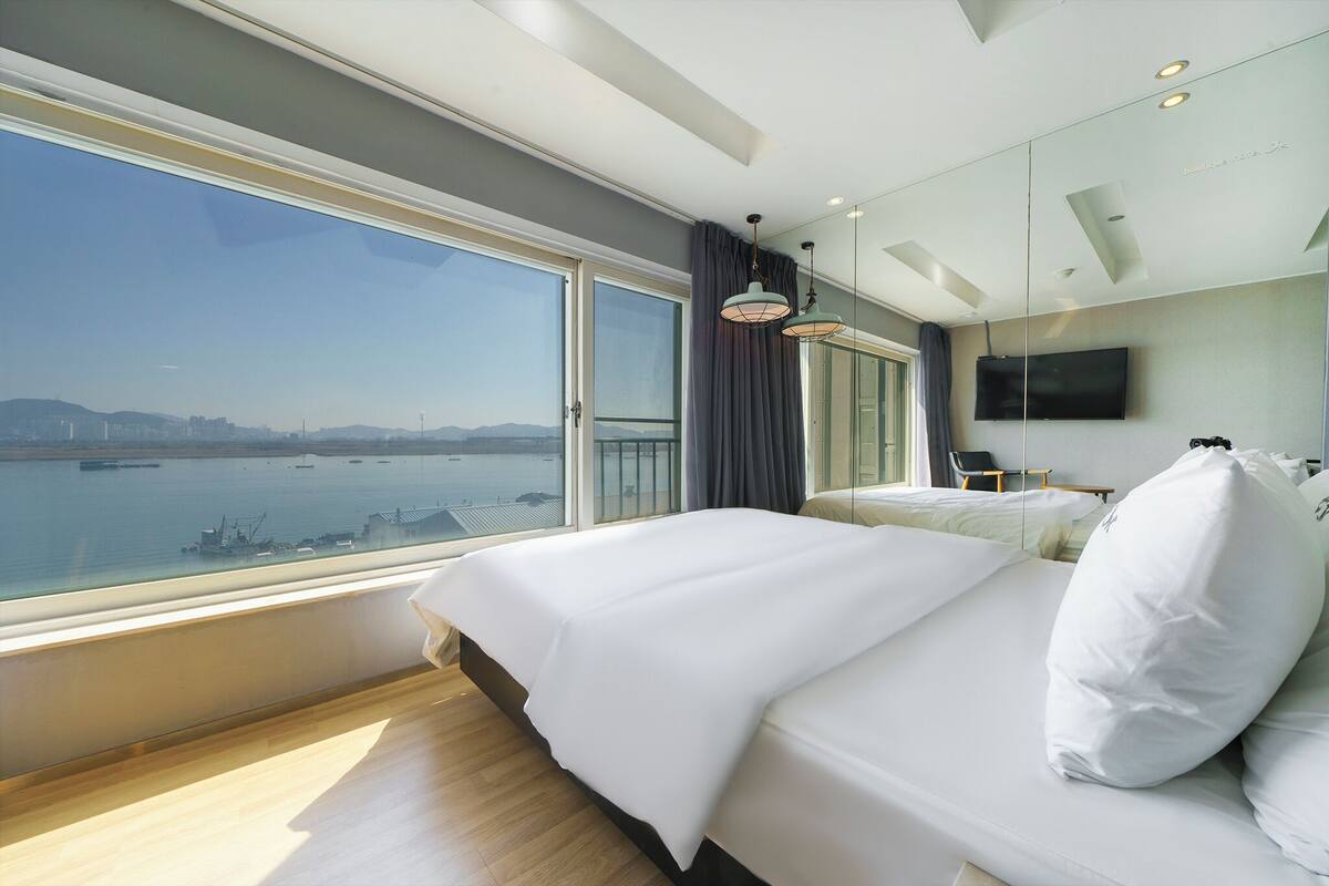 Ein modernes Hotelzimmer mit einem großen Bett, einem Fernseher und Blick auf ein Gewässer.