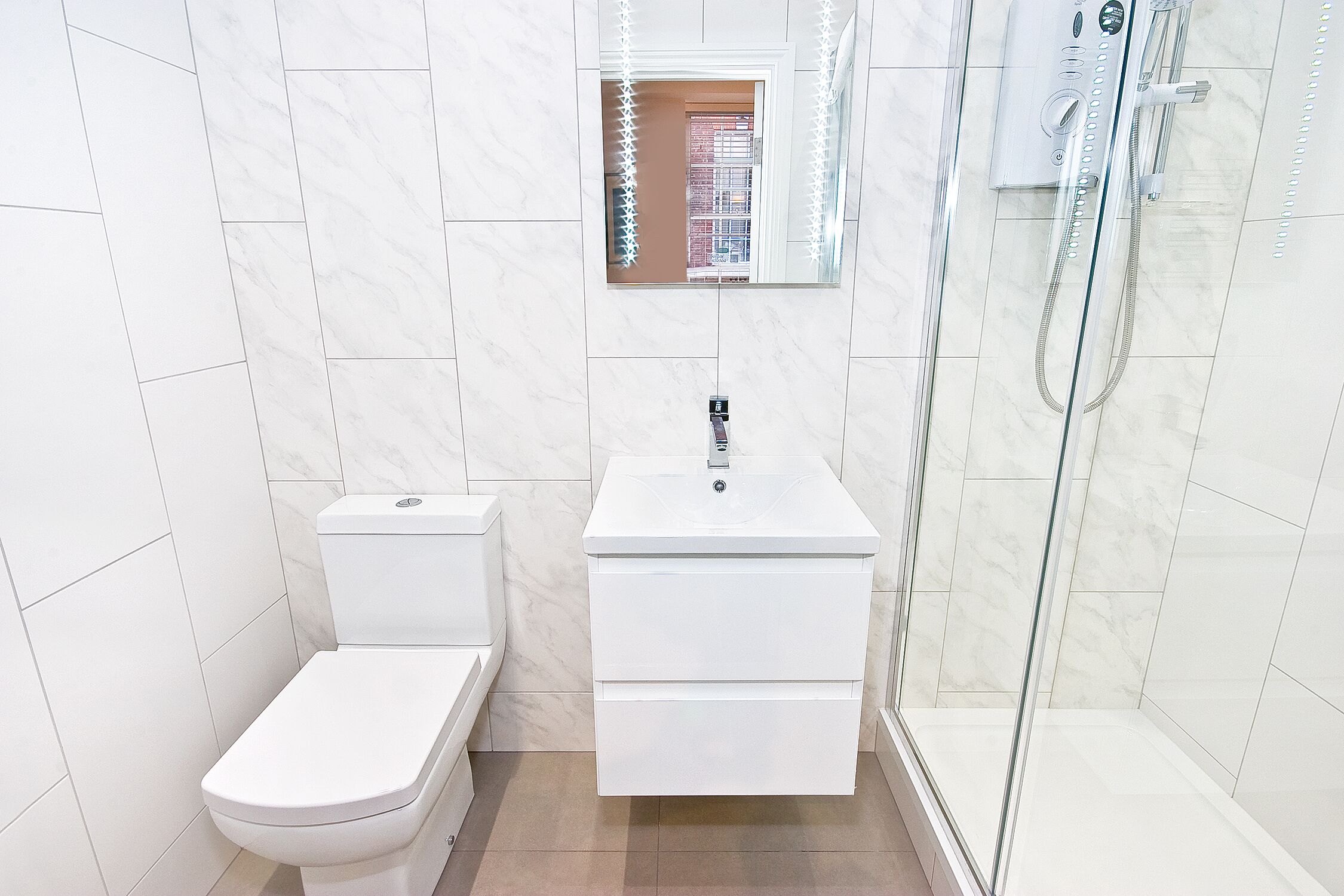 A modern bathroom with a toilet, sink, and glass shower enclosure.
