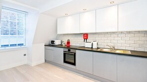 A modern kitchen with grey cabinets, a black countertop, a microwave, a toaster, and a sink.