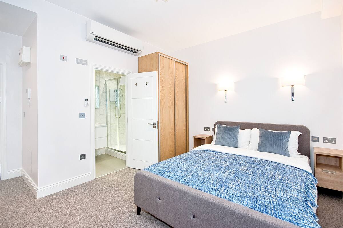 Une chambre à coucher comprenant un lit, une armoire, des tables de chevet et un espace douche.
