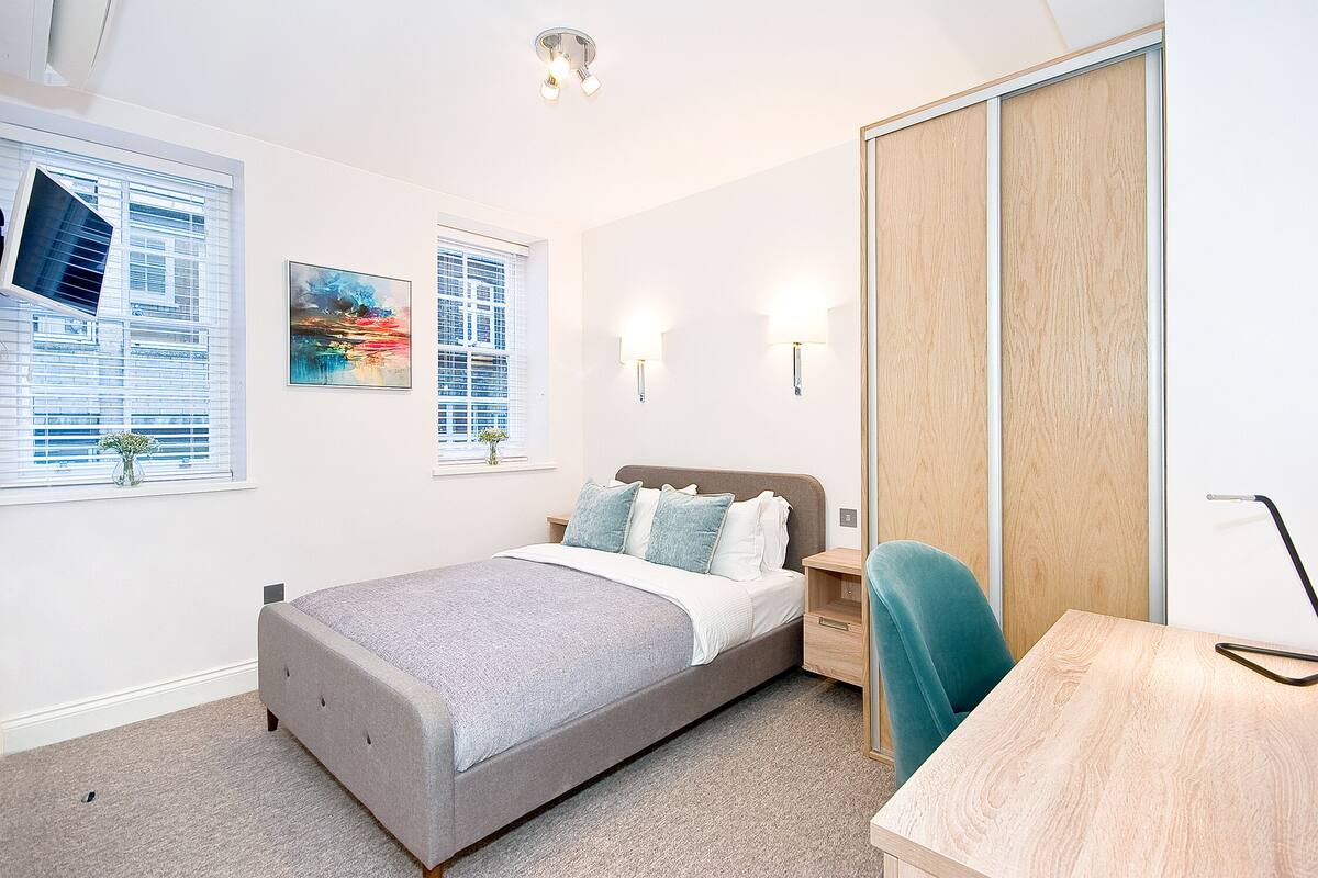 Une chambre à coucher moderne avec un lit, des tables de chevet, un bureau et une armoire.
