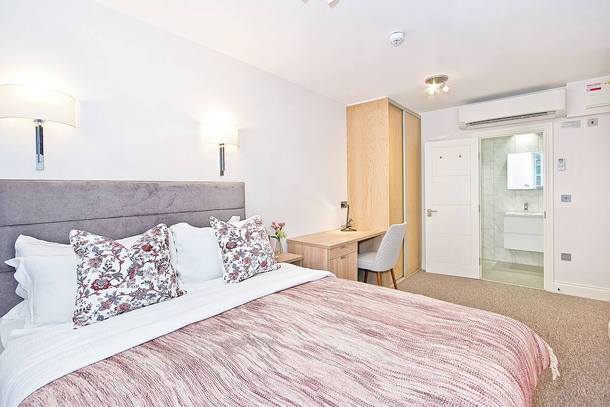 Une chambre d’hôtel moderne avec un grand lit, un bureau et un dressing.