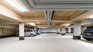 A multi-level parking garage with concrete pillars, tiled floors, and several parked cars. - INhouse Wohnen auf Zeit (Ingolstadt)