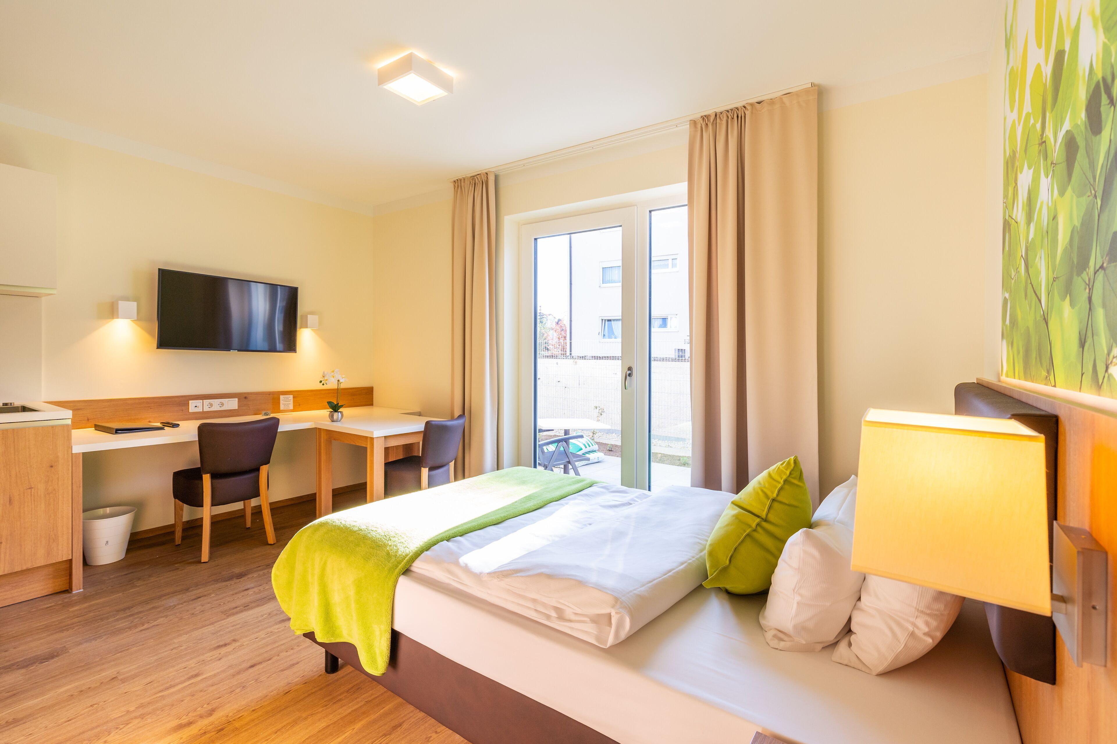 A hotel room with a bed, desk, chair, and a TV.