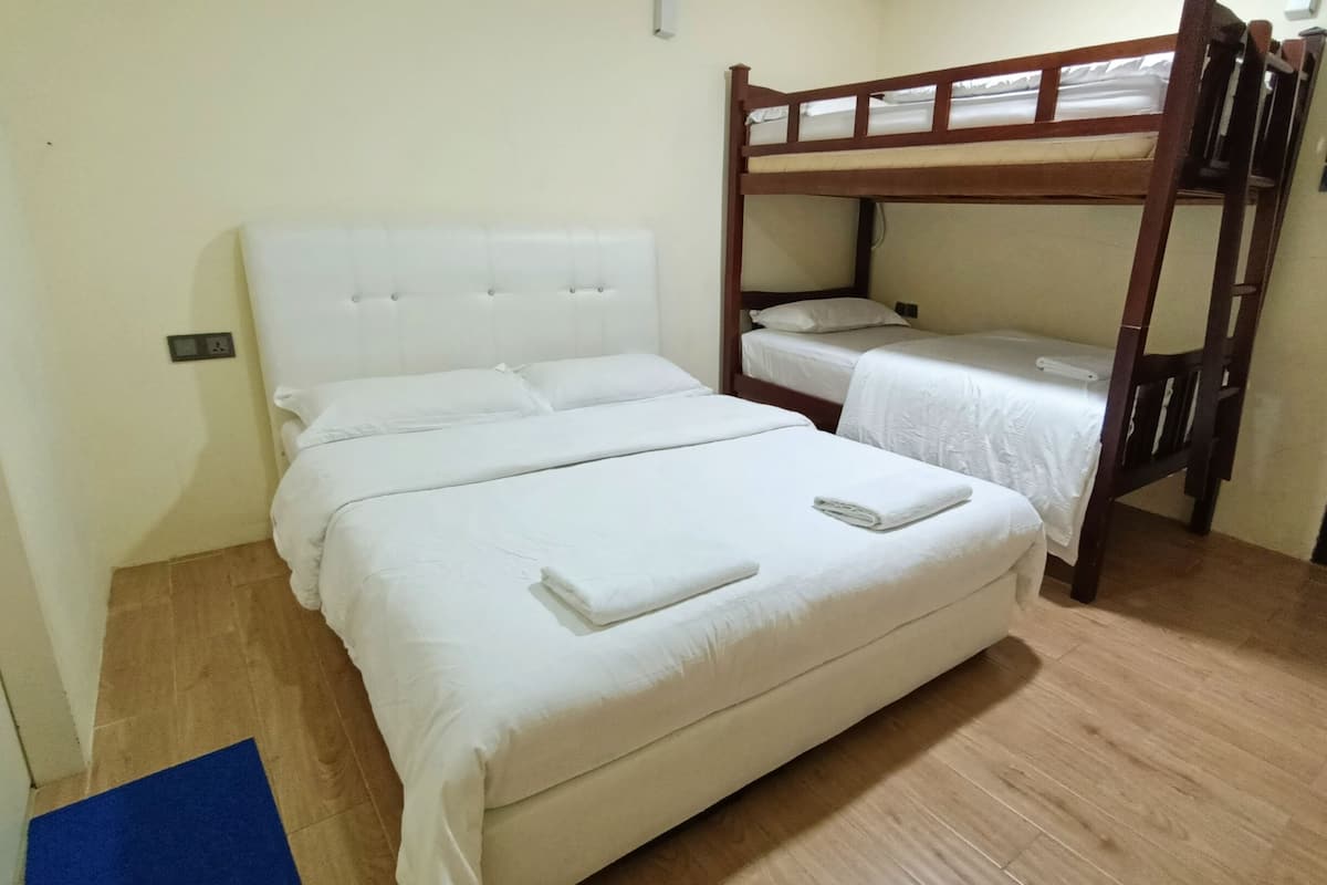 A room with two beds, one with a headboard and one with a bunk bed.