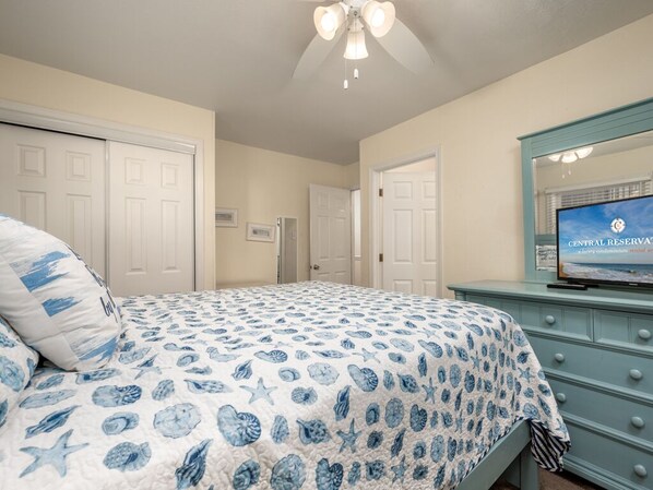 A bedroom with a bed, a dresser, a television, and a ceiling fan. - First Floor Ocean bBock Condo In a Small building (Ocean City)