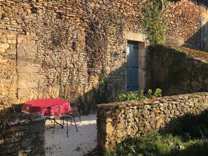 A rustic stone building with a small window and a red table with chairs outside. - Ideal romantic stay, in the countryside 5 minutes from the center (SAINT CYPRIEN)