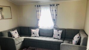 Een woonkamer met een grijze bank, twee gestreepte kussens, een klein houten tafeltje en een zacht tapijt.